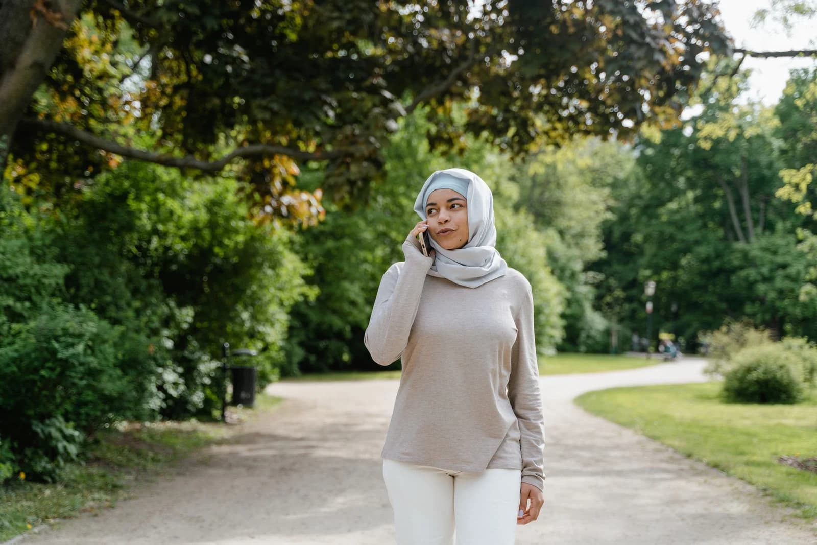 A woman speaking on the phone while walking in a park
