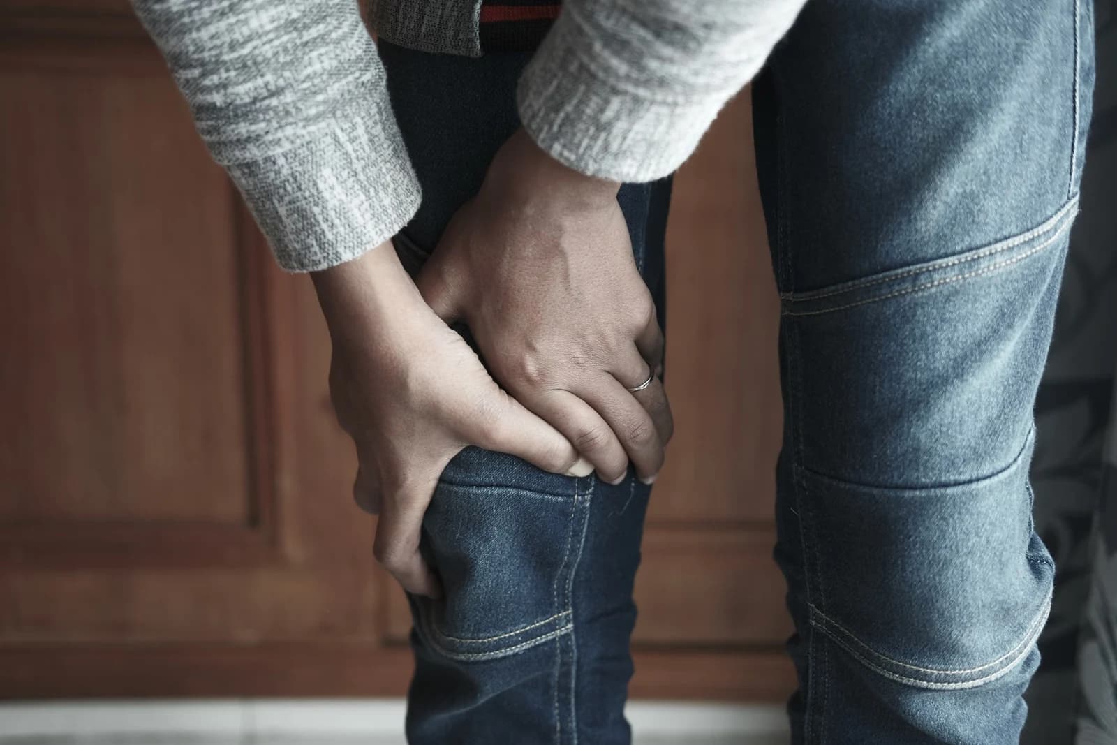 A person holding their knee over their jeans