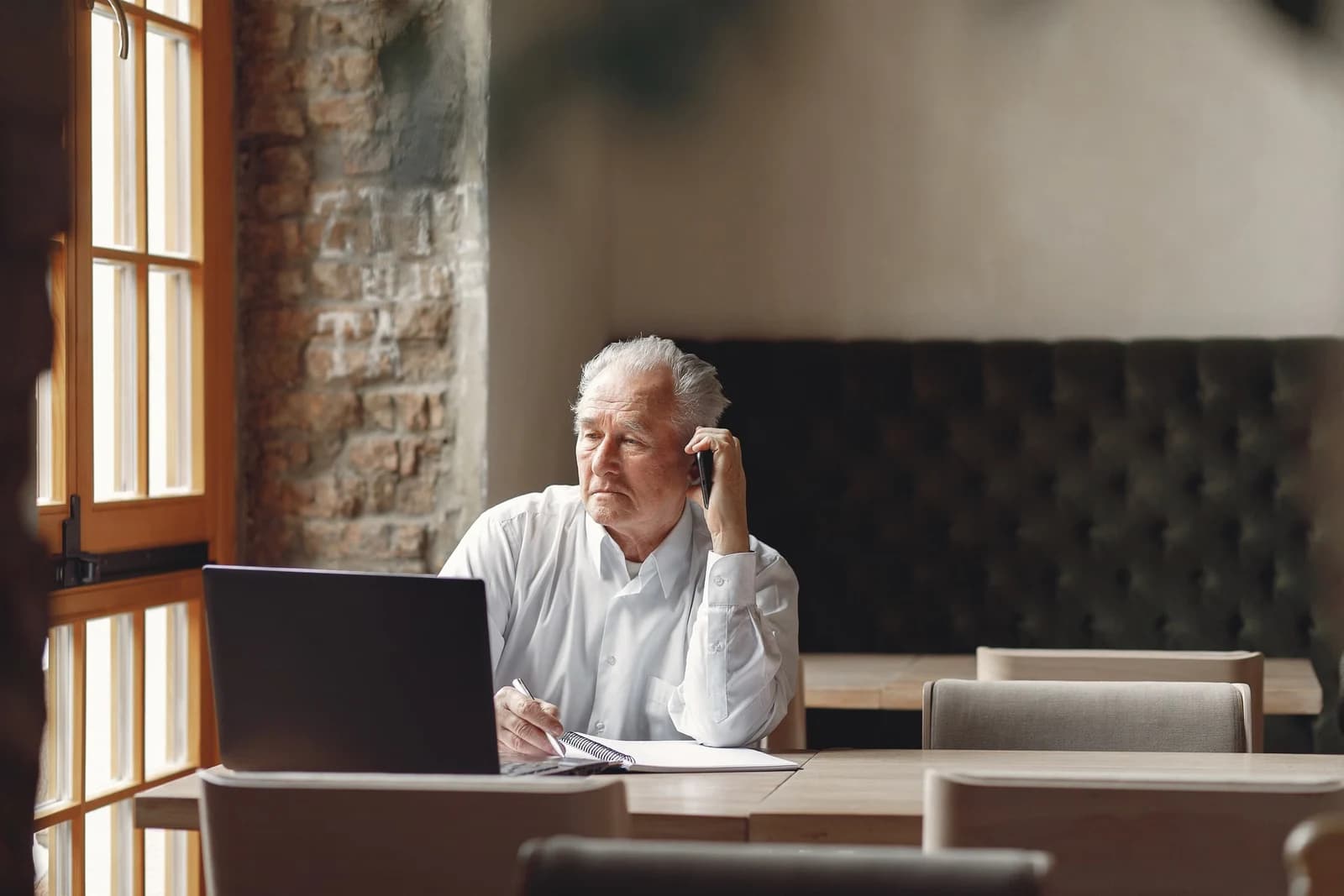 An older man taking notes during a phone call