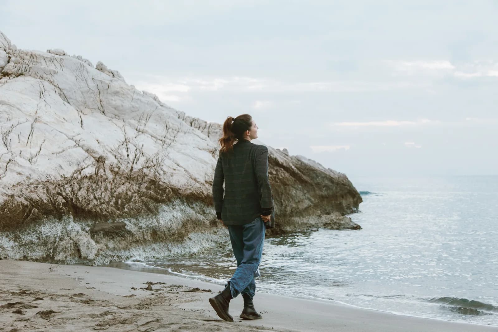 A woman walking along a rocky shoreline