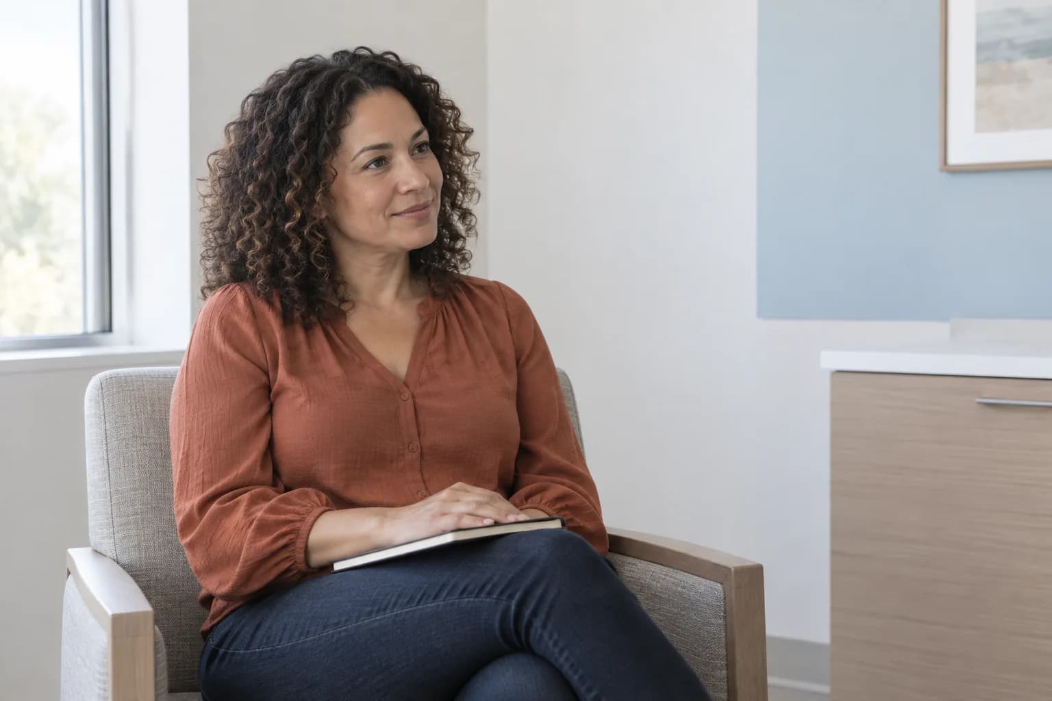 Illustrative image of a woman seated in a consultation room with a notebook