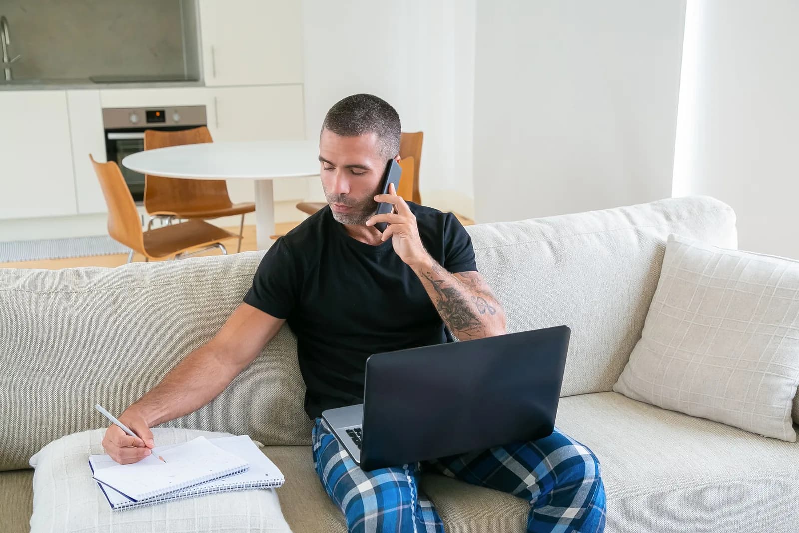 A man taking notes during a phone call at home