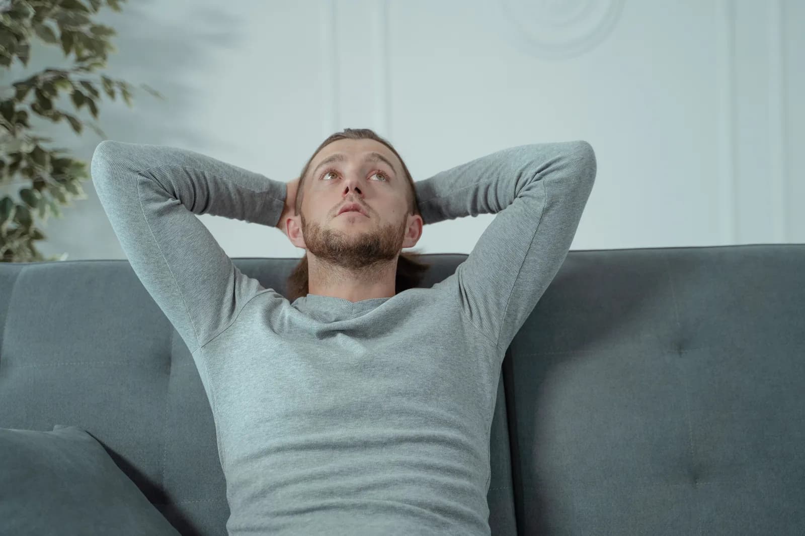 A man resting on a sofa, hands behind his head