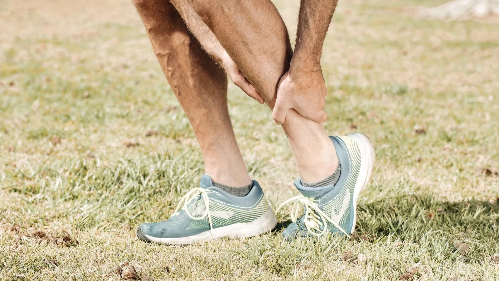 A person holding their calf outdoors