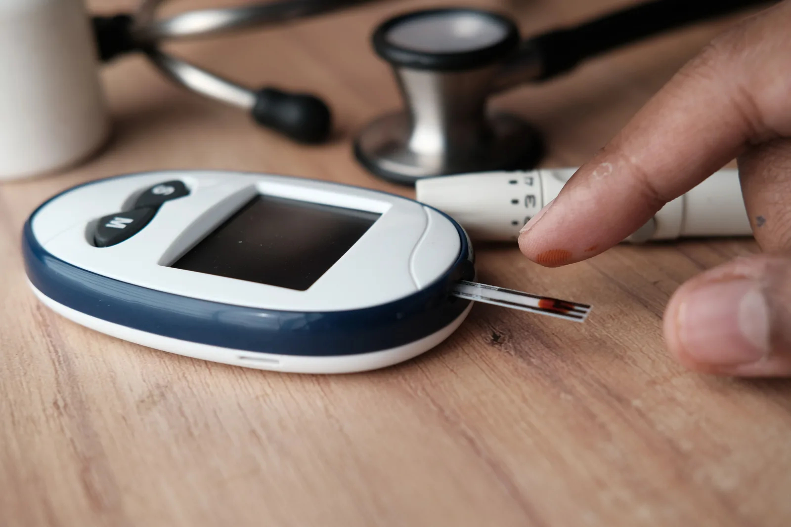 A glucose meter and stethoscope on a wooden table