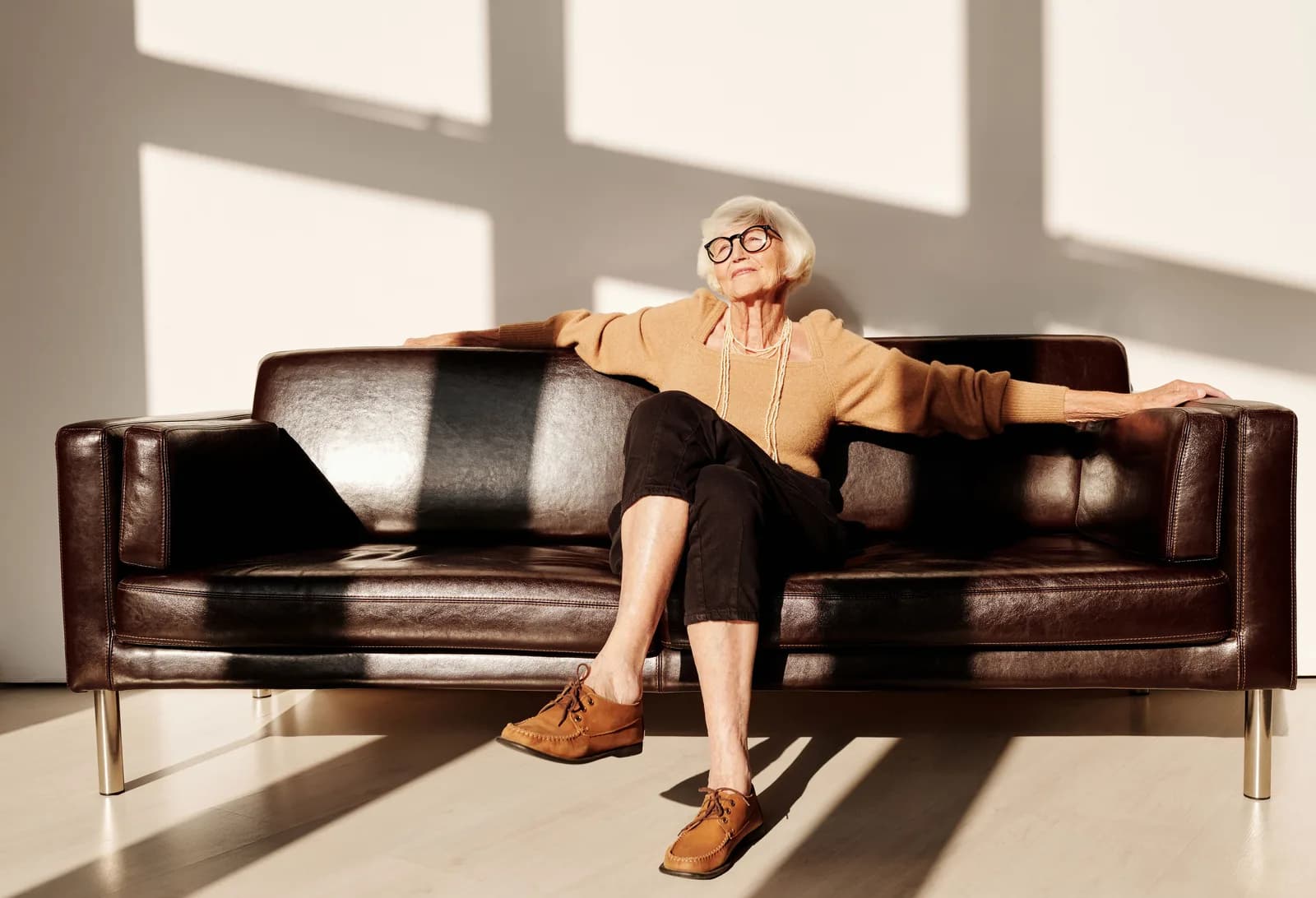 An older woman relaxing on a leather sofa at home